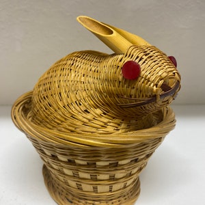 May include: A woven wicker rabbit with red eyes, sitting in a woven wicker basket.