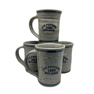 May include: A set of three ceramic mugs with a speckled, matte finish. The mugs are in shades of cream, light gray, and dark gray. Each mug has a simple, minimalist design, perfect for coffee or tea.
