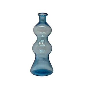 May include: A light blue glass vase with a unique, curvy shape. The vase has a flared base, three rounded sections, and a narrow neck. The transparent glass allows light to pass through, highlighting the blue color. This decorative vase is suitable for displaying flowers or as a standalone art piece.