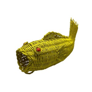 May include: A yellow woven fish-shaped basket with red eyes and an open mouth. The basket is made of tightly woven material and has a tail fin. The fish basket is a decorative item.