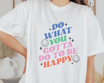 May include: White oversized t-shirt with a colorful graphic print that reads "Do what you gotta do to be happy".