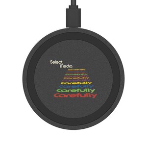 May include: A black wireless charging pad with a black cable. The pad features the words "Select Media" in white, and the word "Carefully" in a rainbow of colours.