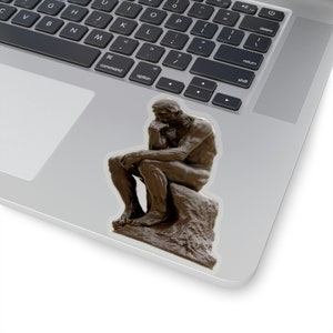 May include: A bronze sculpture of a man sitting with his chin resting on his hand, known as "The Thinker".