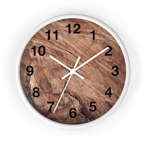May include: A white round clock with black numbers and white hands. The clock face is a wood grain pattern with cracks.