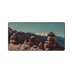 May include: A collection of stacked rocks in a mountainous landscape. The rocks are arranged in a variety of sizes and shapes, creating a visually appealing and balanced composition. The background features a distant mountain range with snow-capped peaks.
