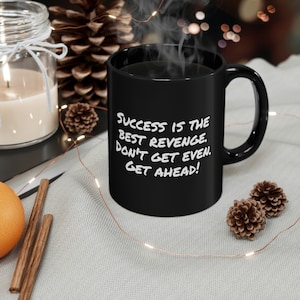 Puede incluir: Taza de café negra con texto blanco que dice "El éxito es la mejor venganza. No te vengues. Adelante!"