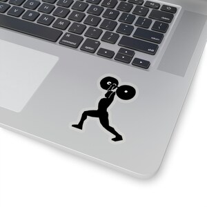 Puede incluir: Silueta negra de una persona levantando una barra de pesas. La persona está en una pose de levantamiento con una pierna hacia adelante y la otra hacia atrás. La barra está por encima de la cabeza de la persona.