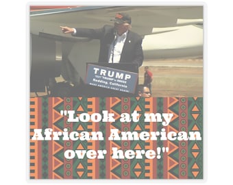 May include: A sticker featuring a photograph of a man speaking at a podium with the text "TRUMP" and "MAKE AMERICA GREAT AGAIN." The sticker also includes the quote, "Look at my African American over here!" The background has an African-inspired pattern.