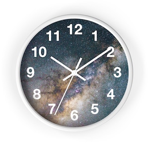 Può includere: Orologio rotondo bianco con sfondo a stampa galattica. Il quadrante dell'orologio ha numeri bianchi da 1 a 12 e lancette delle ore e dei minuti bianche.