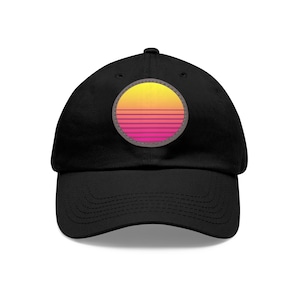 Peut inclure: Une casquette de baseball noire avec un patch de design de coucher de soleil rétro. Le patch est un cercle avec un design de coucher de soleil jaune, orange et rose.