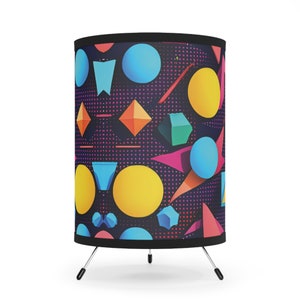 May include: A black and white patterned lampshade with colorful geometric shapes, including circles, triangles, and diamonds. The lampshade is on a black tripod stand.