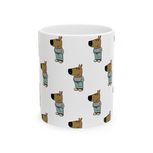 May include: White ceramic mug featuring a repeating pattern of a cartoon dog character. The dog is depicted wearing a gray sweater, blue jeans, and red shoes. The mug is cylindrical and has a glossy finish.