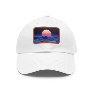Puede incluir: Gorra de béisbol blanca con un parche de cuero marrón que presenta una puesta de sol retro sobre un paisaje morado y azul.
