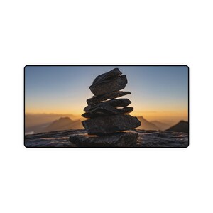 May include: A stack of gray rocks balanced on top of each other against a sunset sky.