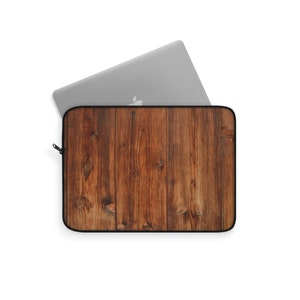 May include: A brown wood grain laptop sleeve with a zipper. The sleeve is designed to protect a laptop from scratches and bumps.