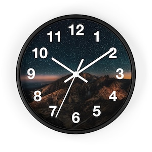 May include: Black round clock with white numbers and hands. The clock face features a starry night sky with a mountain range in the foreground.