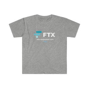 May include: A heather gray t-shirt with the FTX logo in white and teal. The text "RISK MANAGEMENT DEPT." and "2022" are printed below the logo. The shirt is made of a soft, comfortable material.