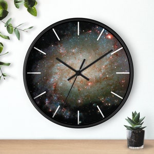 May include: A black clock with white numbers and hands. The clock face features a colorful image of a galaxy.