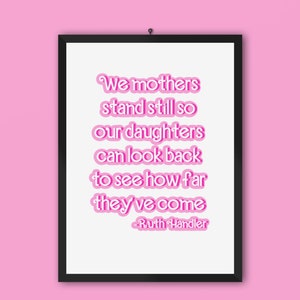 May include: A framed print with a pink quote that reads "We mothers stand still so our daughters can look back to see how far they've come - Ruth Handler".