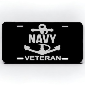 May include: Black metal license plate with a white anchor and the words "NAVY VETERAN".