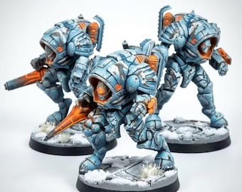 May include: Three miniature robot figures with light blue and white camouflage armor. Each figure features orange accents, a glowing orange eye, and a pointed orange weapon. They stand on circular bases with white snow-like texture details.