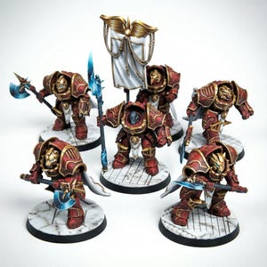 Op de afbeelding: Een set van zes miniatuur krijgersfiguren in versierd rood en goudkleurig harnas. Elk figuur staat op een ronde voet met een wit marmerpatroon. Ze zijn uitgerust met diverse wapens die voorzien zijn van lichtblauwe klingen.