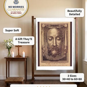 Holy Face plush blanket hung flat from a wooden quilt stand beside a home prayer corner with a crucifix, candles and white lilies