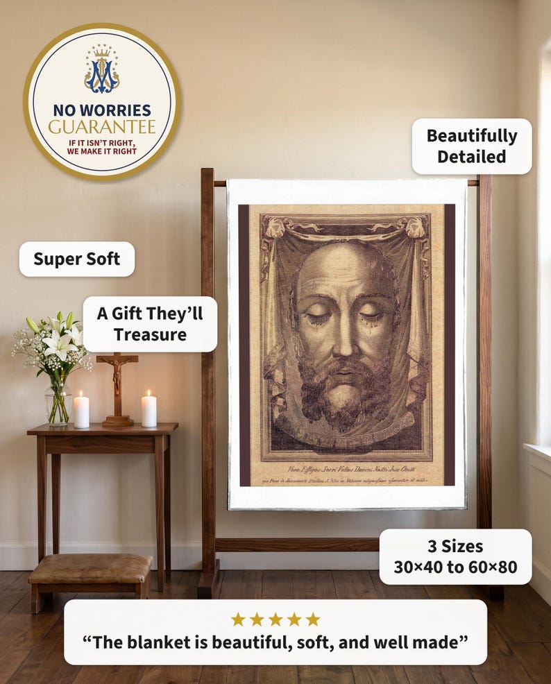 Holy Face plush blanket hung flat from a wooden quilt stand beside a home prayer corner with a crucifix, candles and white lilies