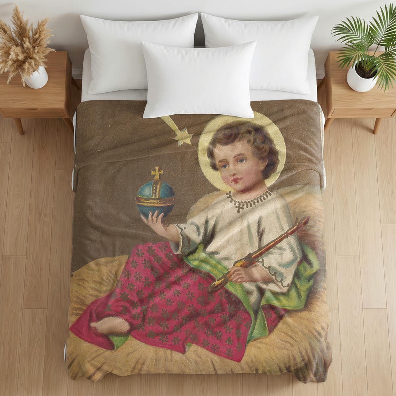 Plush blanket featuring a vintage religious illustration of a cherub with a halo holding a globe and paintbrush, draped on a bed with white pillows and wooden nightstands