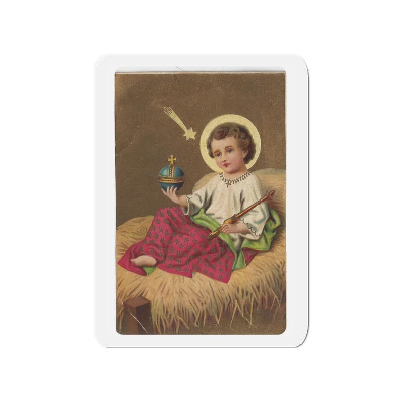 Die-cut magnet featuring a religious illustration of the Christ Child with a halo, seated on straw, holding a jeweled orb and paintbrush, with a star above against a brown background