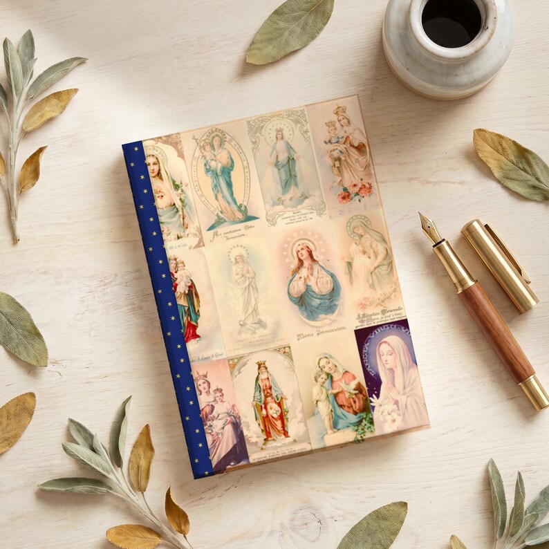 View of Queenship of Mary lined journal, with the prayer typeset on the back cover, navy and gold star spine, pen flat lay