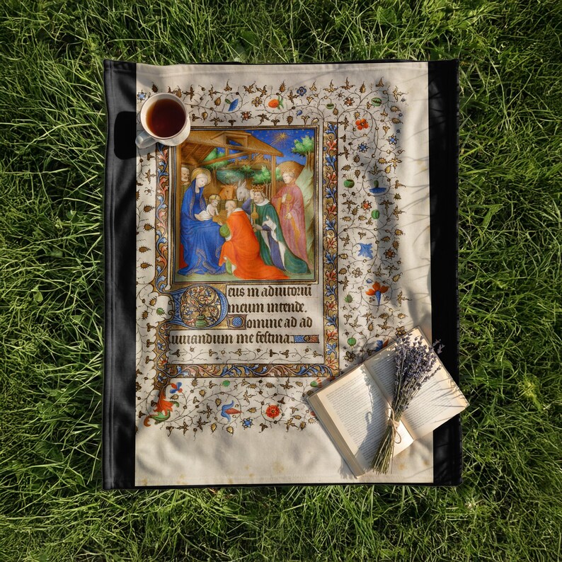 Nativity plush blanket laid on the grass with a cup of tea and an open book