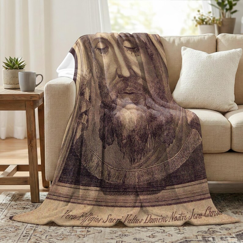 Holy Face plush blanket draped over the arm of a cream sofa