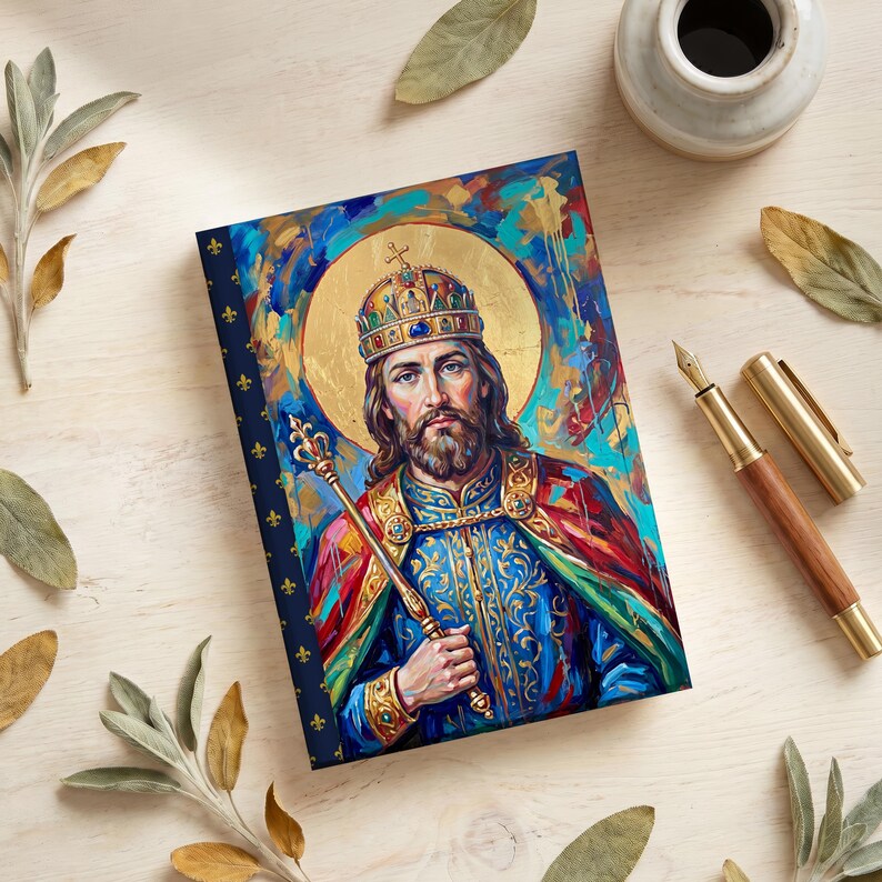View of St. Stephen of Hungary lined journal, with the prayer typeset on the back cover, navy and gold fleur-de-lis spine, pen flat lay