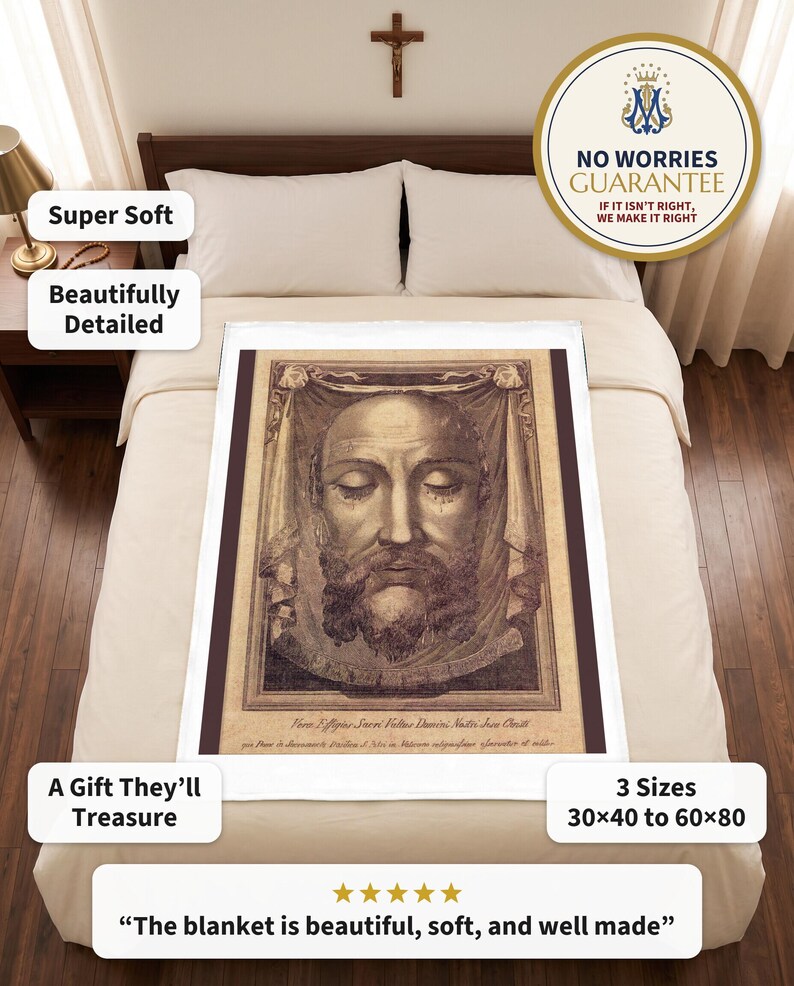 Holy Face plush blanket spread flat on a neatly made bed under a wooden crucifix, a rosary on the nightstand