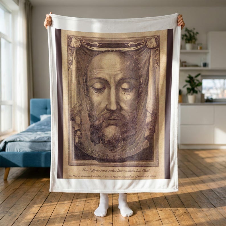 Holy Face plush blanket held up to show its full size in a bright room