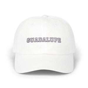 White dad hat with 'GUADALUPE' embroidered on the front panel in collegiate-style navy and white outlined lettering, photographed straight-on against a white background