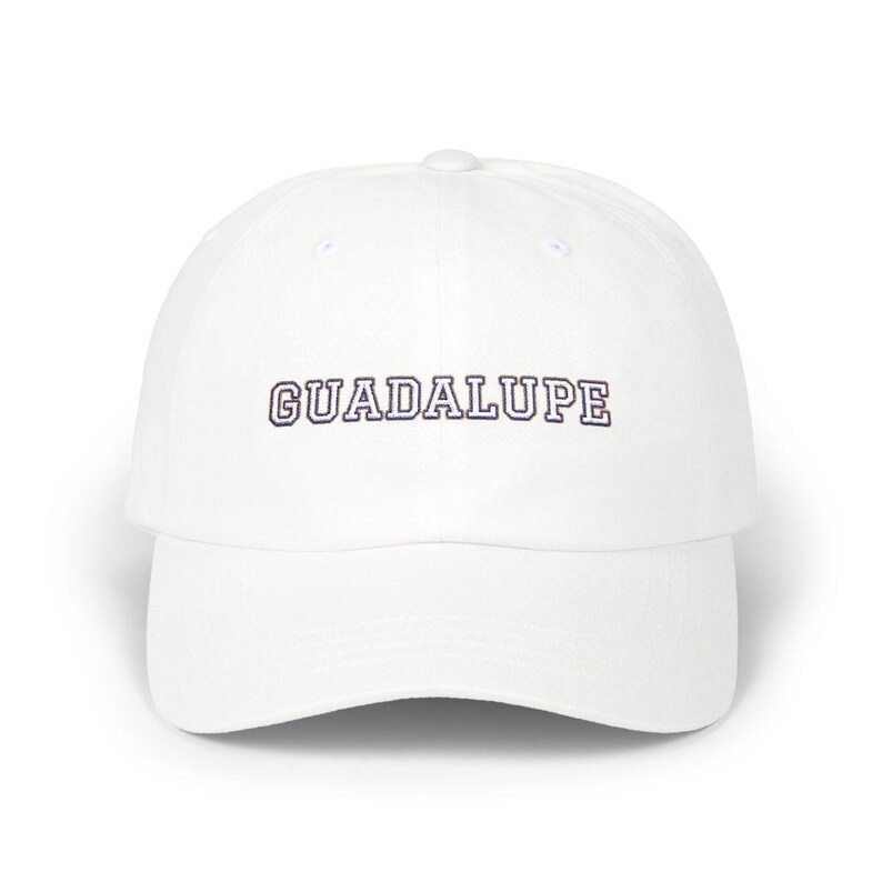 White dad hat with 'GUADALUPE' embroidered on the front panel in collegiate-style navy and white outlined lettering, photographed straight-on against a white background