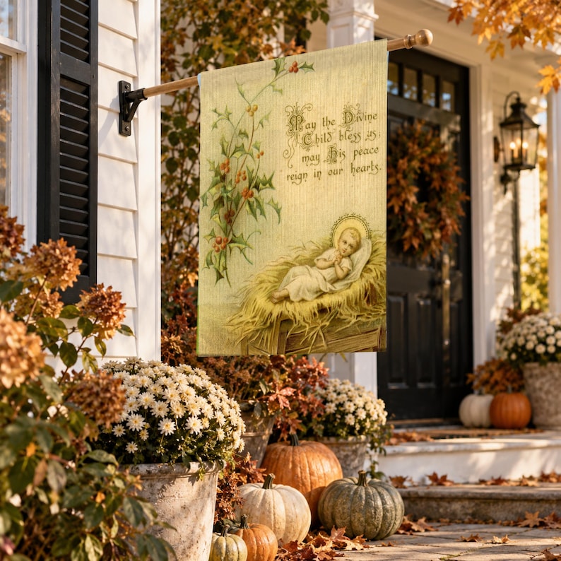 Nativity garden flag in the large size, hung from a wall pole beside a front door with an autumn wreath