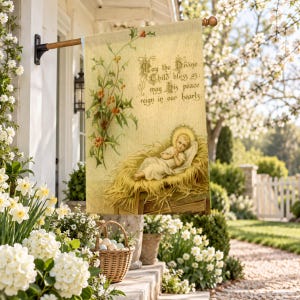 Nativity garden flag in the large size, hung from a wall pole over a spring porch of daffodils