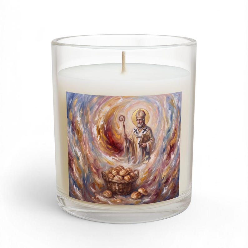 Clear glass candle with cream-colored wax and wooden wick, featuring a religious artwork label depicting St. Nicholas with a golden halo holding a staff, surrounded by swirling gold and purple brushstrokes with a basket of bread at the bottom