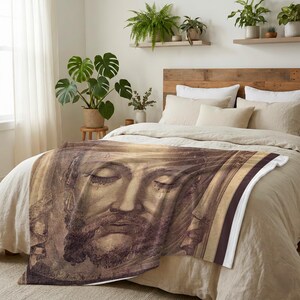 Holy Face plush blanket spread across the foot of a bed with a wooden headboard