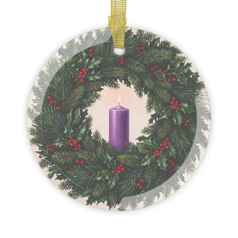 Round glass ornament with gold ribbon hanger featuring an illustration of a purple candle centered in a wreath of evergreen branches, holly leaves, and red berries, representing the First Sunday of Advent