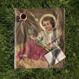 Christmas plush blanket laid on the grass with a cup of tea and an open book
