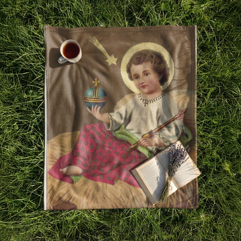 Christmas plush blanket laid on the grass with a cup of tea and an open book