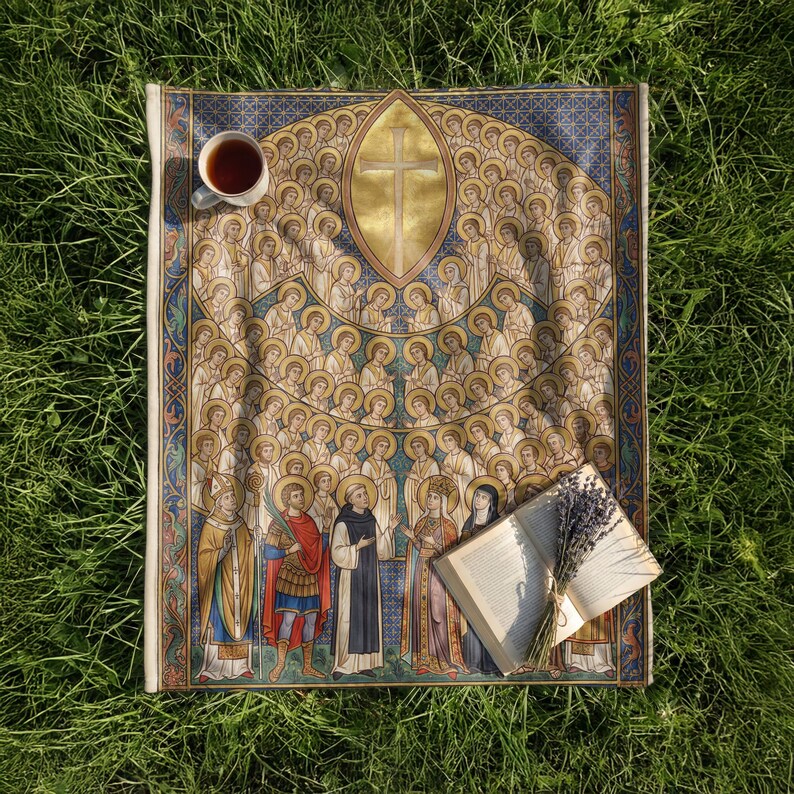 All Saints plush blanket laid on the grass with a cup of tea and an open book