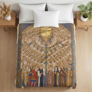 Plush blanket draped over a bed with white pillows, featuring religious iconography of All Saints with figures in gold halos arranged in rows against a blue and gold patterned background, displayed on wooden nightstands with potted plants