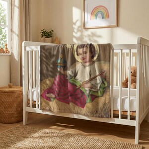 Christmas plush blanket hung over the rail of a white crib with a teddy bear inside