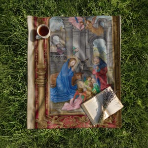 Nativity plush blanket laid on the grass with a cup of tea and an open book