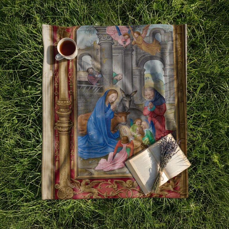 Nativity plush blanket laid on the grass with a cup of tea and an open book